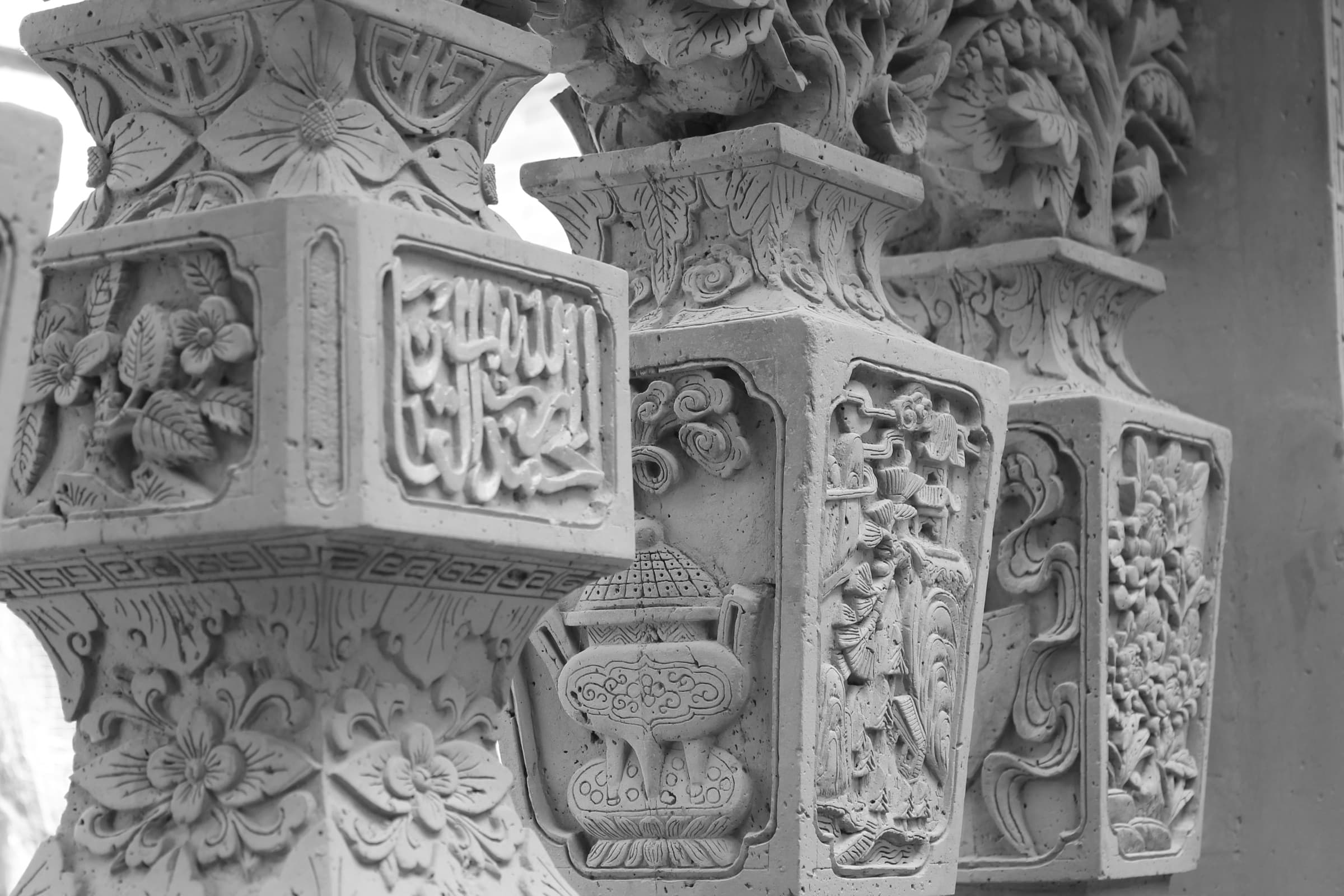 Panneau de pierre grise finement sculpté où une calligraphie arabe est enchâssée dans des cartouches et des rinceaux de facture chinoise.