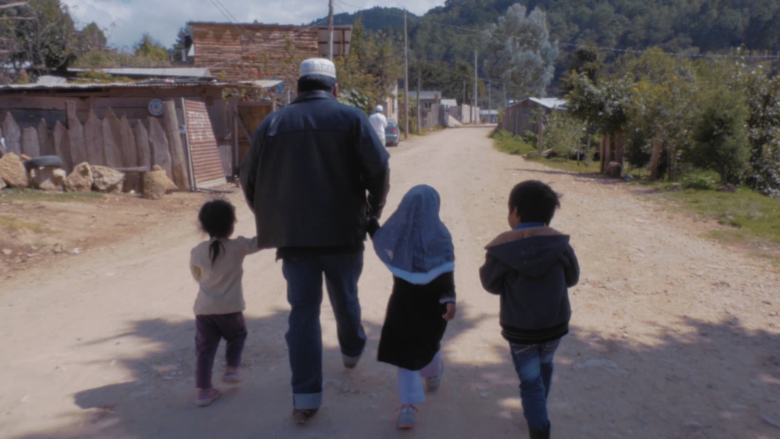 Un homme marche avec trois enfants sur un chemin du Chiapas